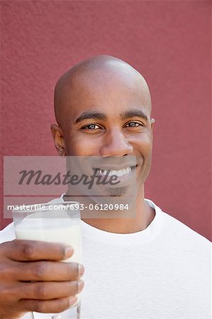 Portrait of a happy young man with milk glass over colored background