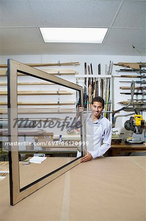 Portrait d'un jeune homme heureux sur cadre d'ensemble dans l'atelier de travail