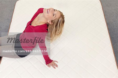 Femme heureuse reposante sur matelas tête de retour en magasin de meubles