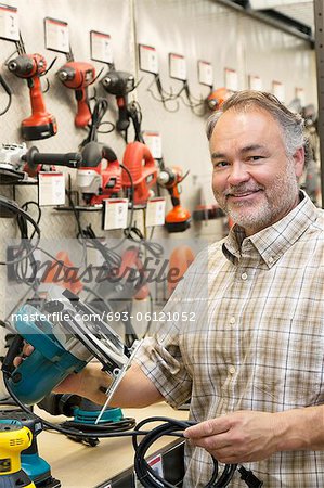 Portrait of a happy hardware store owner with electric saw