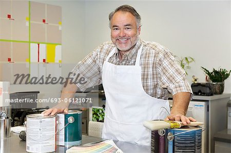 Portrait of a cheerful mature sales clerk with paint can in hardware store
