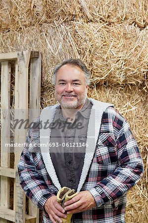 Portrait of a happy mature man in front of hay stack