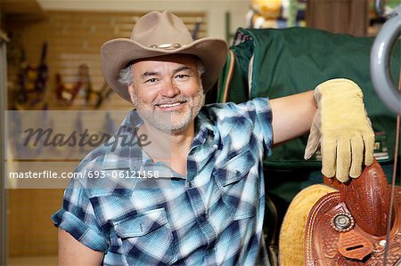Portrait d'un cow-boy mature heureux en magasin de fourrage