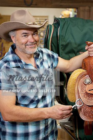 Portrait of a happy cowboy with riding tack in feed store