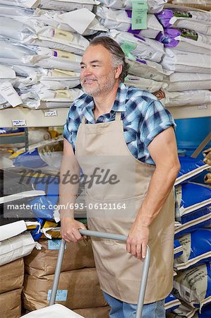 Happy mature man pushing cart in feed store