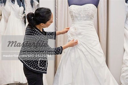 Vue latérale d'une femme mûre, ajustant la robe de mariée en boutique