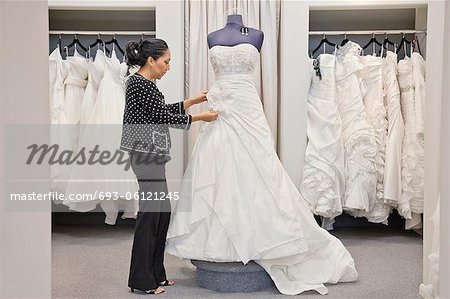 Vue latérale d'un employé mature réglage de robe de mariage élégant dans bridal boutique