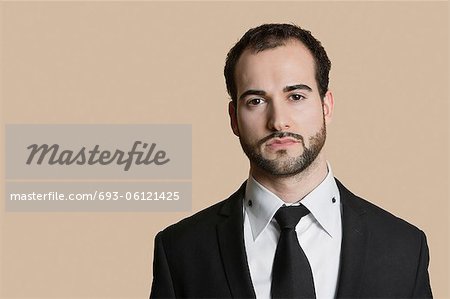 Portrait of young businessman with short hair and beard over colored background