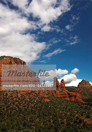 Some cliffs in the Arizona desert near Sedona. Red Rock, lush with plants in the summer. Blue slightly cloudy sky
