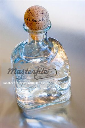 Bottle of Patron Silver Tequila on a reflective metal surface.