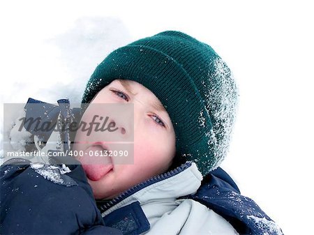 Young boy playing in snow, sticking his tongue out
