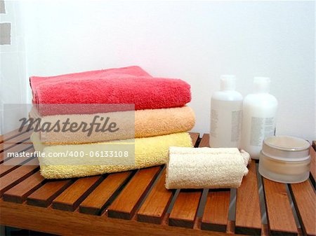 Spa or bathroom accessories: stack of colorful towels, loofah sponge, lotions, shampoos, creams