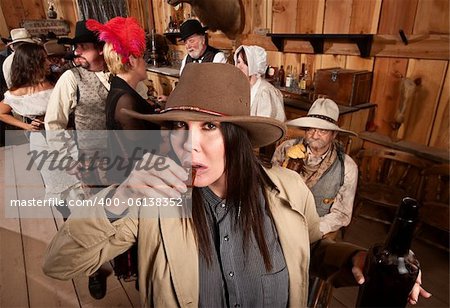 Cowgirl with bottle sipping whiskey from a shot glass