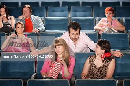 Rude bearded man talking to ladies in a theater