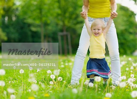 Mother playing with baby girl on dandelions field