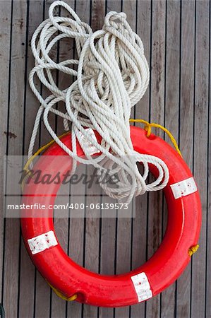 Safe support  circle with rope. Rescue water red life buoy on wooden background of ship or boat. Helpful object.