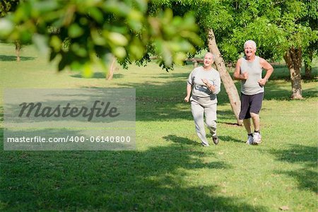 Active retirement, senior couple running and exercising in city park. Copy space