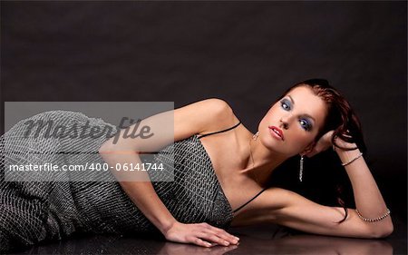 pretty brunette wearing silver fashion dress on black background