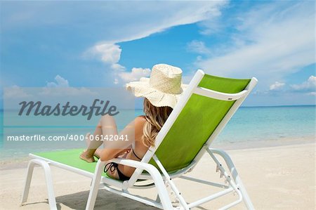 Young woman with hat relaxing on a deck chair Young woman with hat relaxing on a deck chair