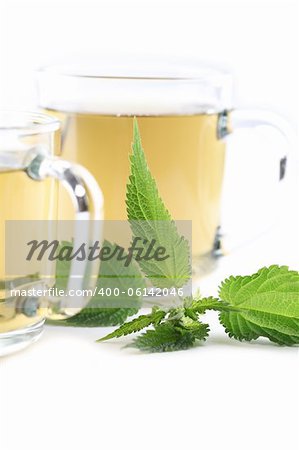 Nettle and freshly made nettle tea in glass cups isolated on white background. Shallow dof, focus on nettle