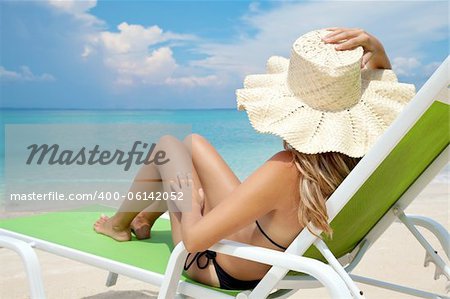 Young woman with hat relaxing on a deck chair Young woman with hat relaxing on a deck chair