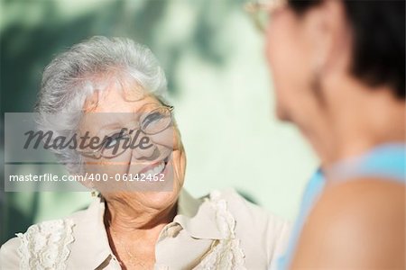 Active retirement, two elderly female friends talking on bench in public park