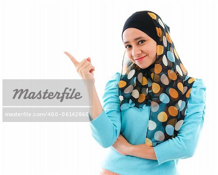 Cute young Muslim woman pointing on empty space, isolated on white