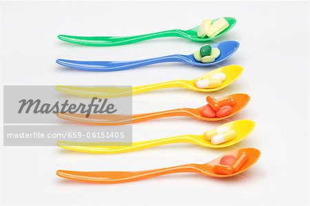 A row of spoons with vitamin tablets