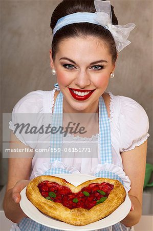 A retro-style girl holding a heart-shaped puff pastry cake