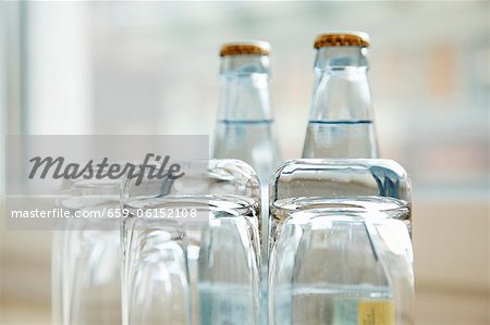 Upside down water glasses with bottles of water in the background