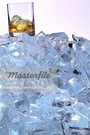 A whiskey glass on a mountain of ice cubes