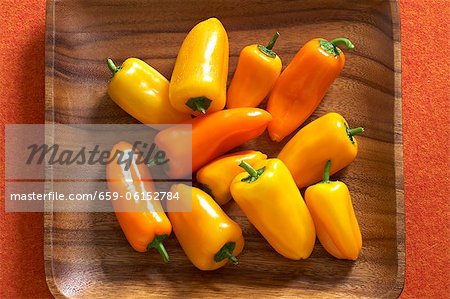 Yellow and orange mini peppers in a wooden crate