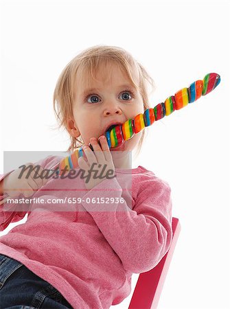 A small child eating a giant lolly