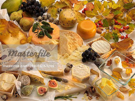 Various types of cheeses, fruit, butter, quail's eggs and autumnal leaves