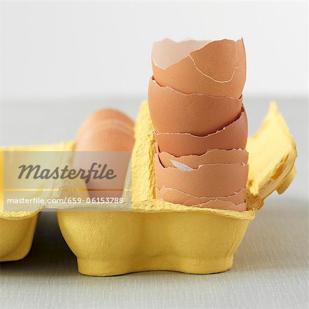 A stack of egg shells in a yellow egg box