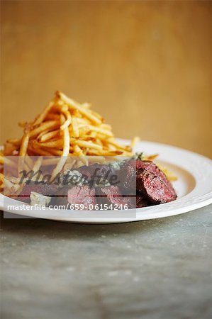 Tranches de Steak au fromage bleu et frites sur une plaque blanche