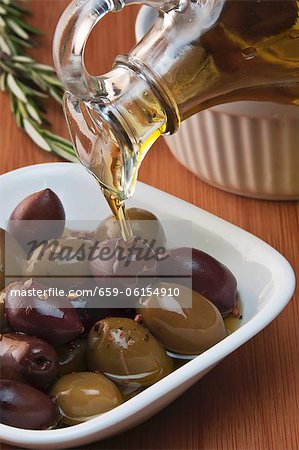 Olive Oil Pouring Over Mixed Olives