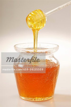 Drizzling hors une cuillère acrylique dans un pot de miel
