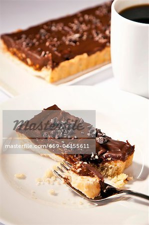 Morceau de la tarte au chocolat noisette avec croûte sablée ; Fourche ; Espresso