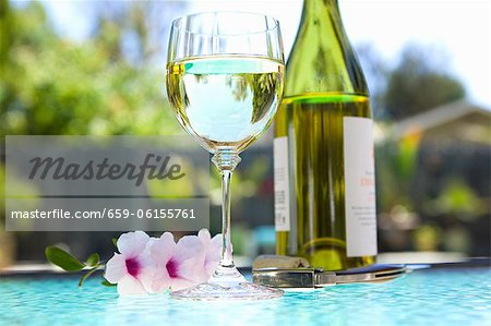 Verre et bouteille de vin blanc sur une Table en plein air ; Près de la piscine