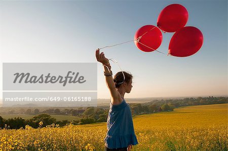 Girl carrying balloons in field