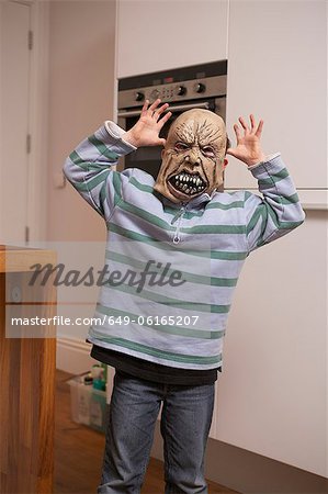 Boy wearing Halloween mask in kitchen