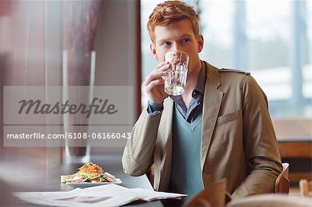Homme assis dans un restaurant et de l'eau potable Homme assis dans un restaurant et de l'eau potable