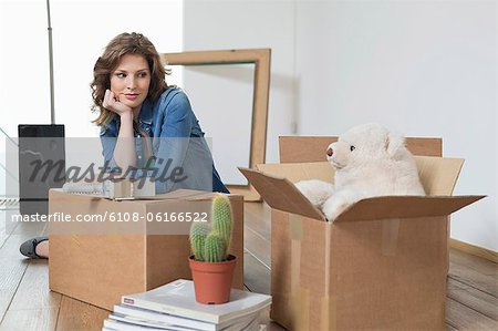 Woman leaning on a cardboard box and looking at a teddy bear