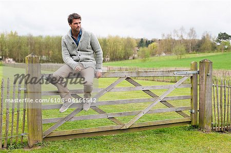 Mann sitzt auf dem Tor einer Hütte