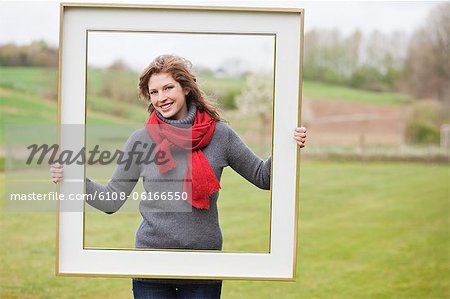 Portrait d'une femme debout avec un frame dans un parc