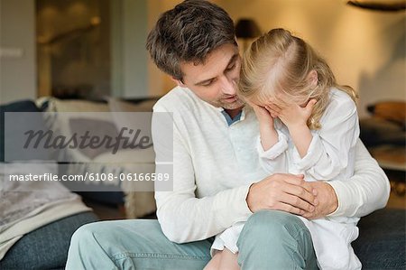Man holding his cute daughter covering her eyes with hands