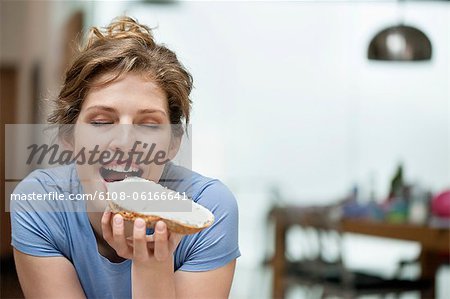 Femme manger pain grillé avec de la crème diffuser sur elle Femme manger pain grillé avec de la crème diffuser sur elle