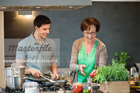 Woman assisting her son to cook food in the kitchen