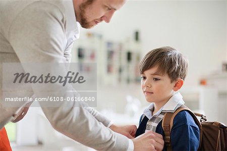 Man preparing his son for school